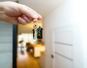 Chave de imóvel sendo entregue após regularização da propriedade, ilustrando o procedimento de adjudicação compulsória extrajudicial.