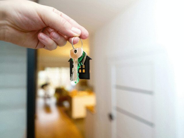 Chave de imóvel sendo entregue após regularização da propriedade, ilustrando o procedimento de adjudicação compulsória extrajudicial.